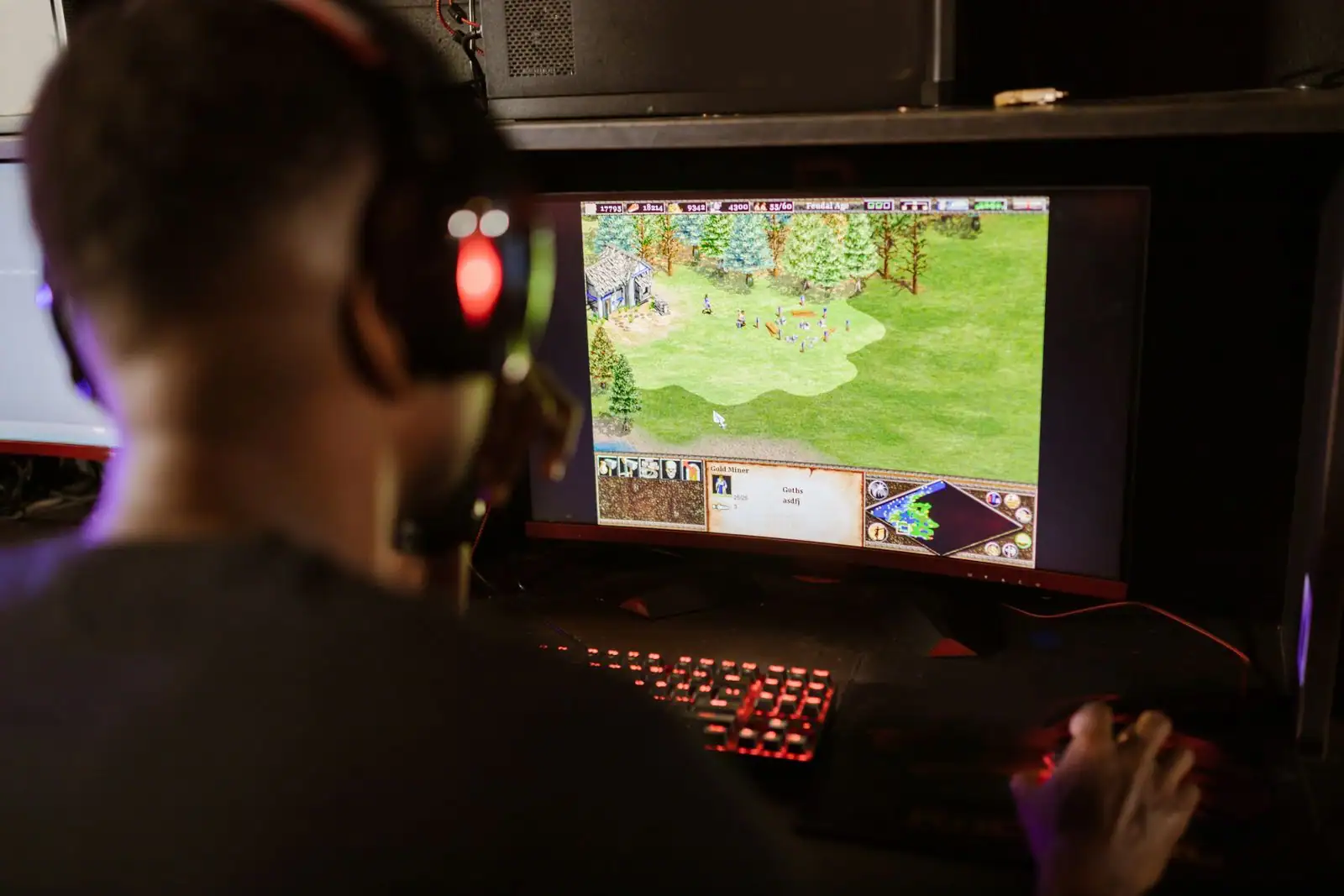 Un joueur casque sur les oreilles devant un jeu vidéo affiché sur l'écran de son ordinateur