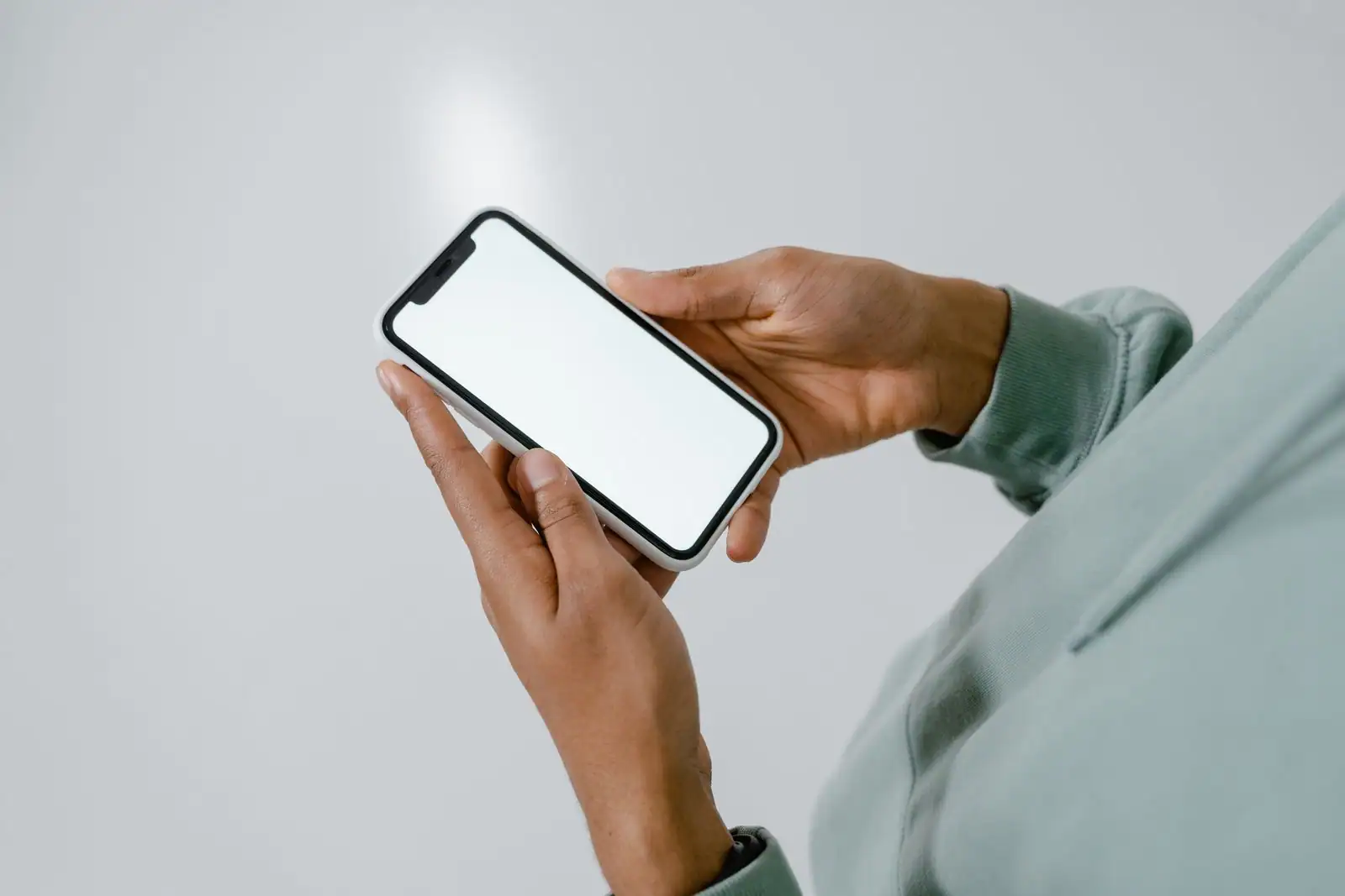 Une personne tient un smartphone à l'écran vierge entre ses mains