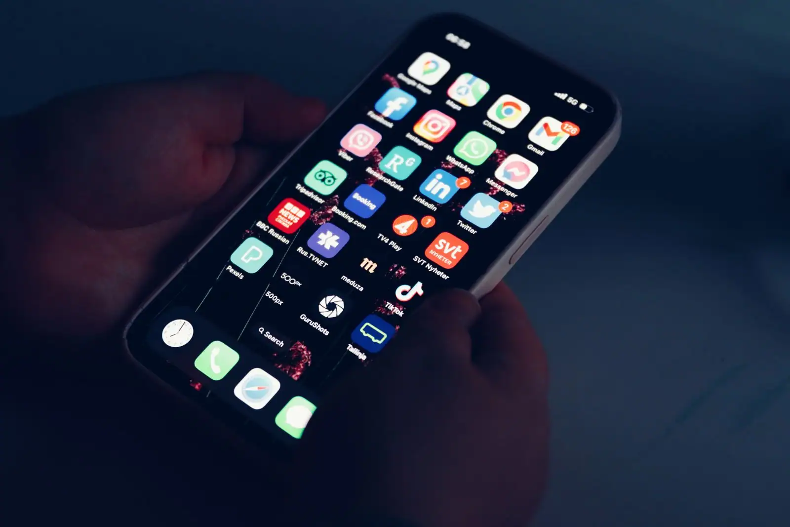 Écran d'un smartphone tenu en main affichant une grille d'icônes d'applications mobiles.
