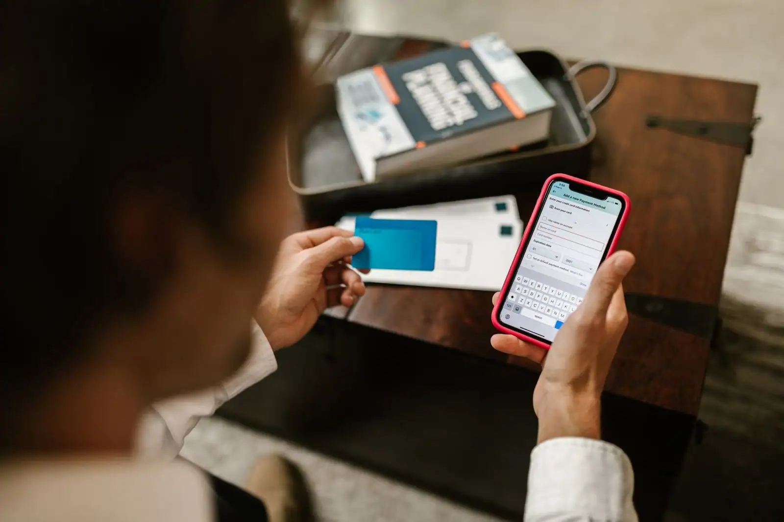 Personne tenant une carte bancaire et saisissant un moyen de paiement dans une application sur smartphone.