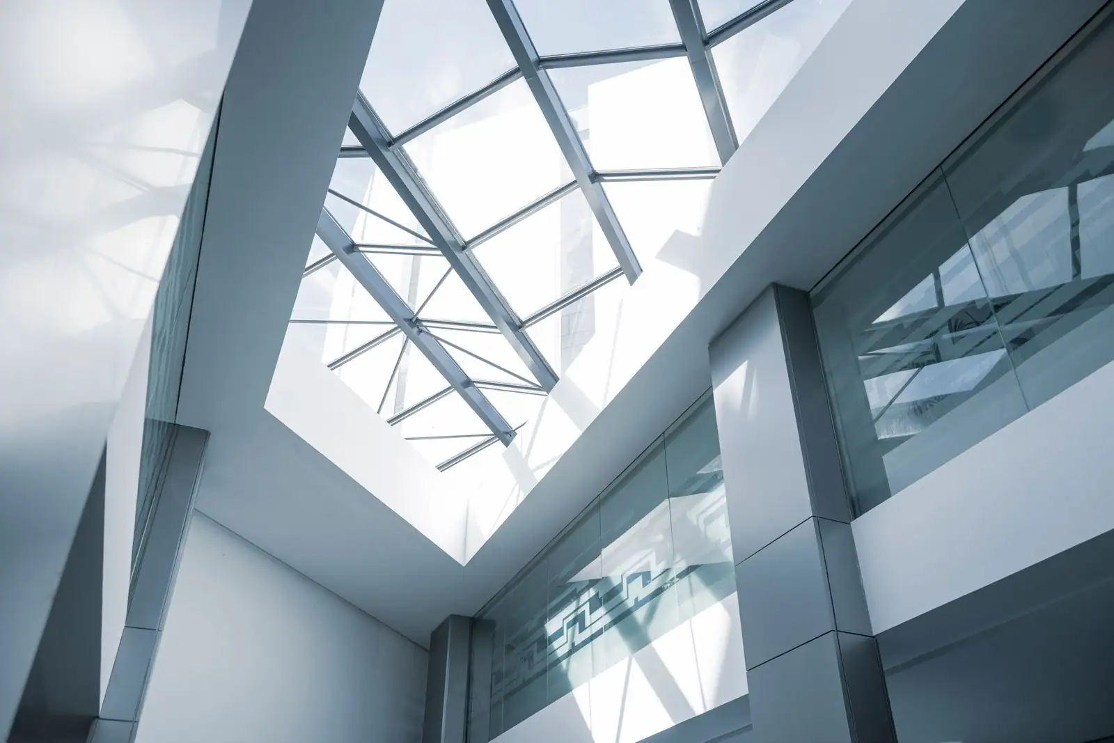 Verrière à ossature métallique apparente au plafond d'un bâtiment moderne, vue en contre-plongée