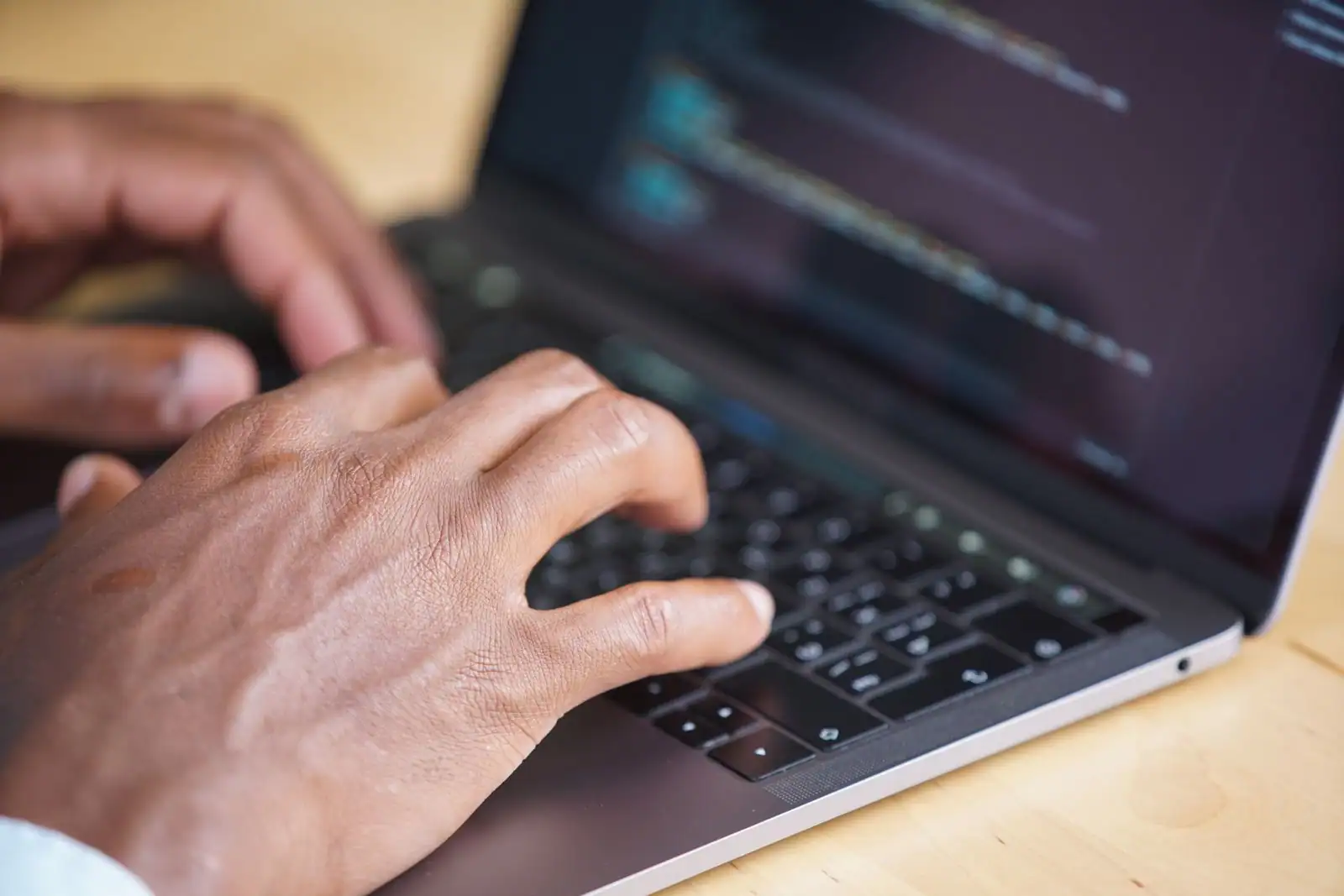 Mains d'une personne tapant sur le clavier d'un ordinateur portable posé sur un bureau