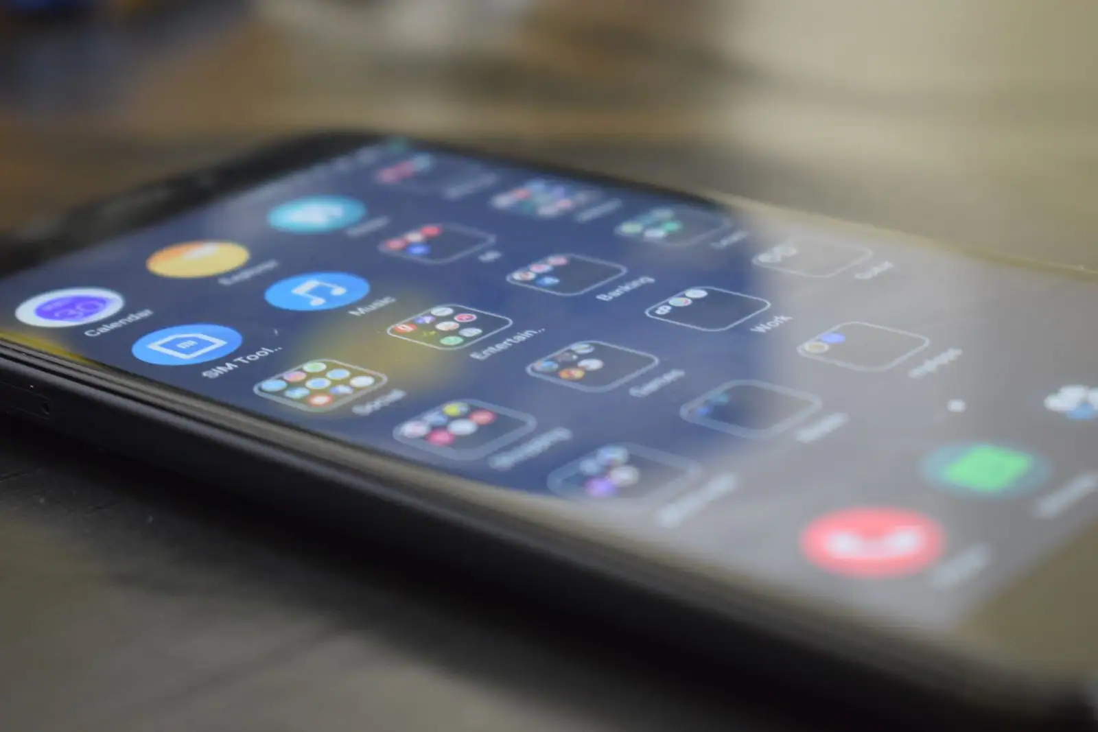 Écran de smartphone posé sur une table affichant une grille d'icônes d'applications colorées.
