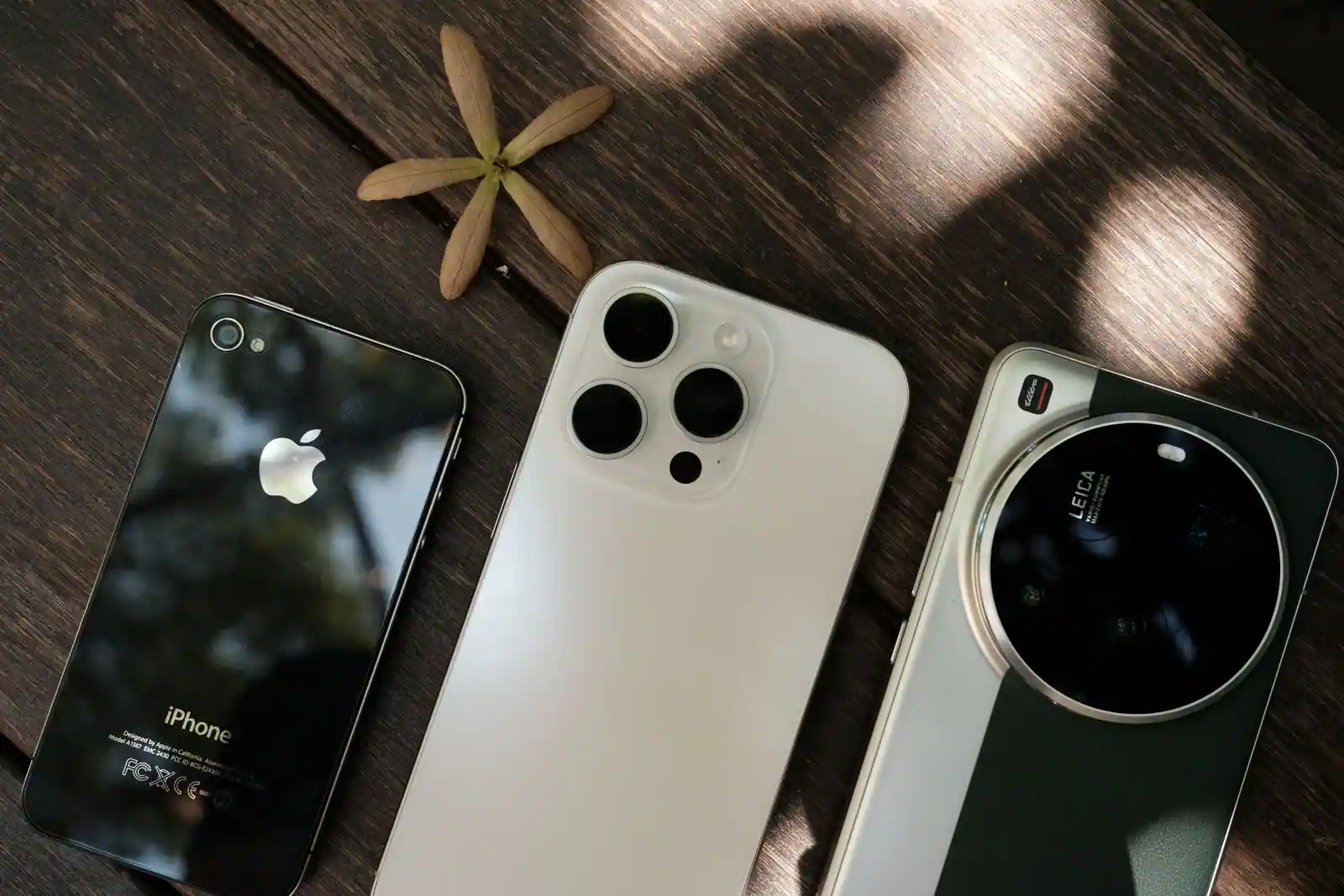 Trois smartphones de modèles différents posés côte à côte sur une table en bois