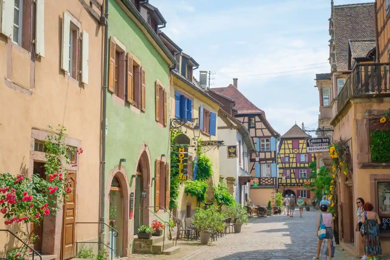 Maisons alsaciennes à colombages aux façades colorées le long d'une rue pavée typique de la région
