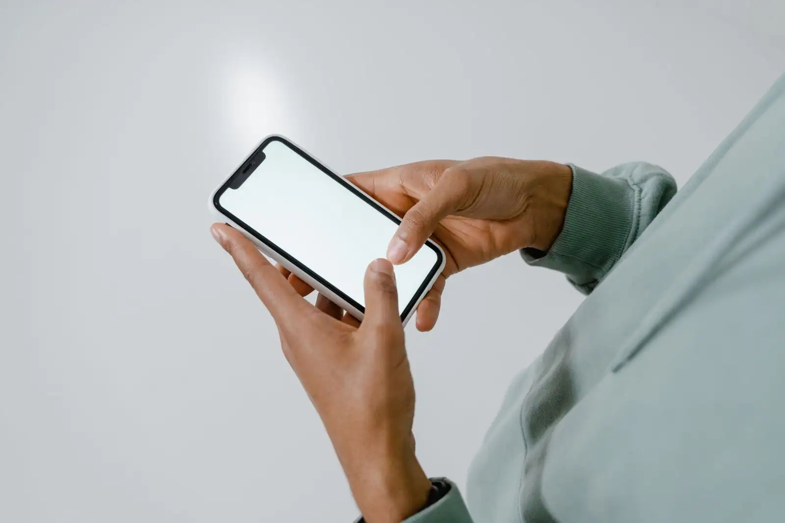 Mains tenant un iPhone à l'écran vierge, comme pour consulter les informations de l'appareil.