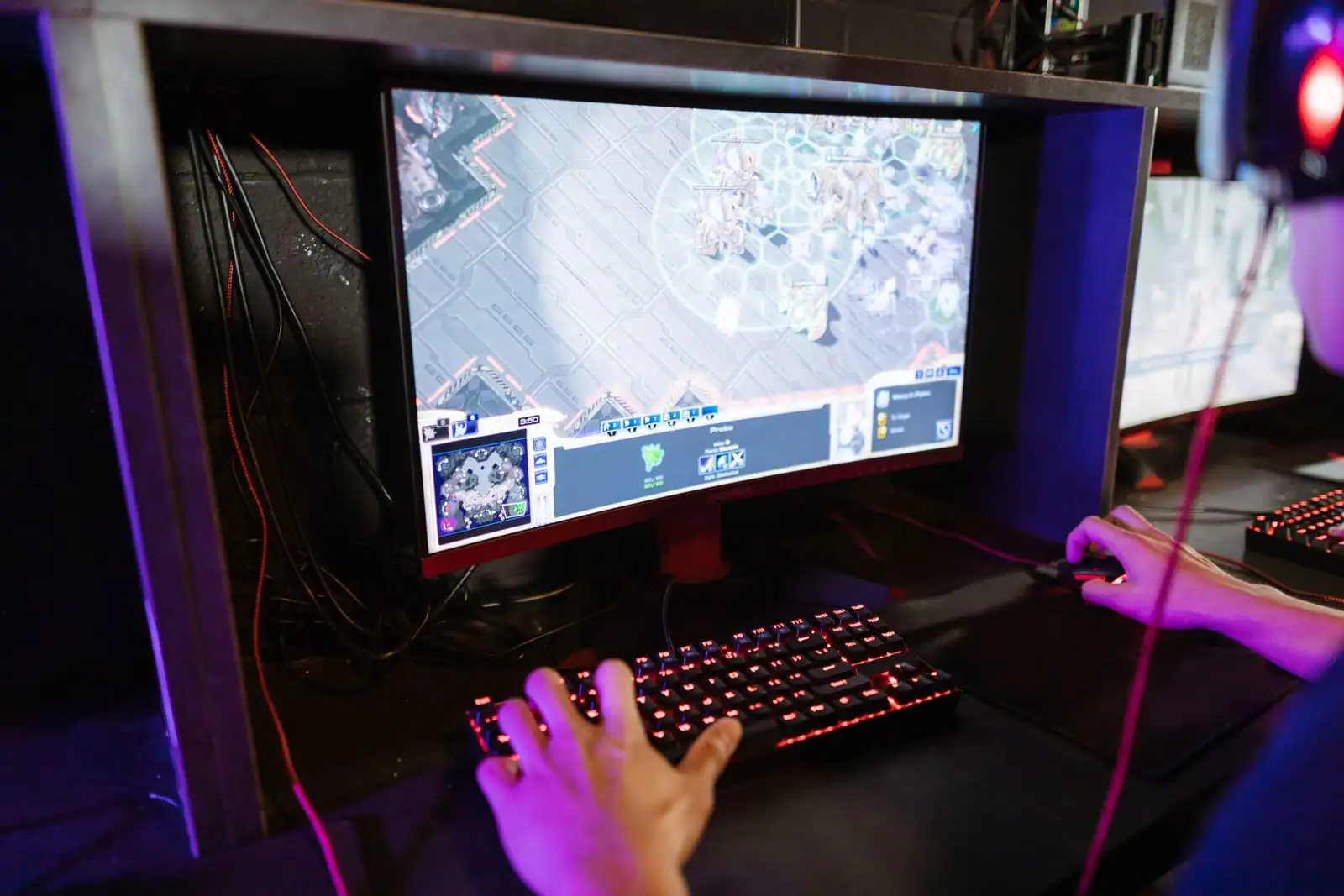 Joueur devant un écran d'ordinateur PC, clavier rétroéclairé et souris en main