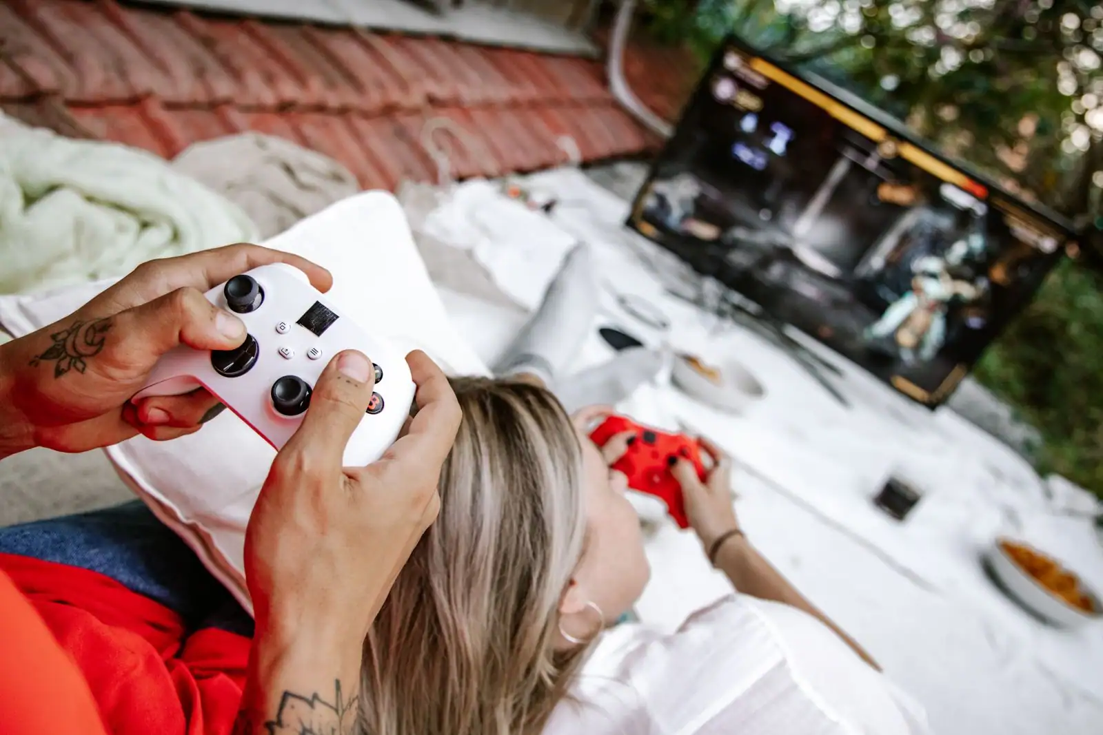Deux personnes jouant aux jeux vidéo, manettes en main, devant un écran de jeu allumé.
