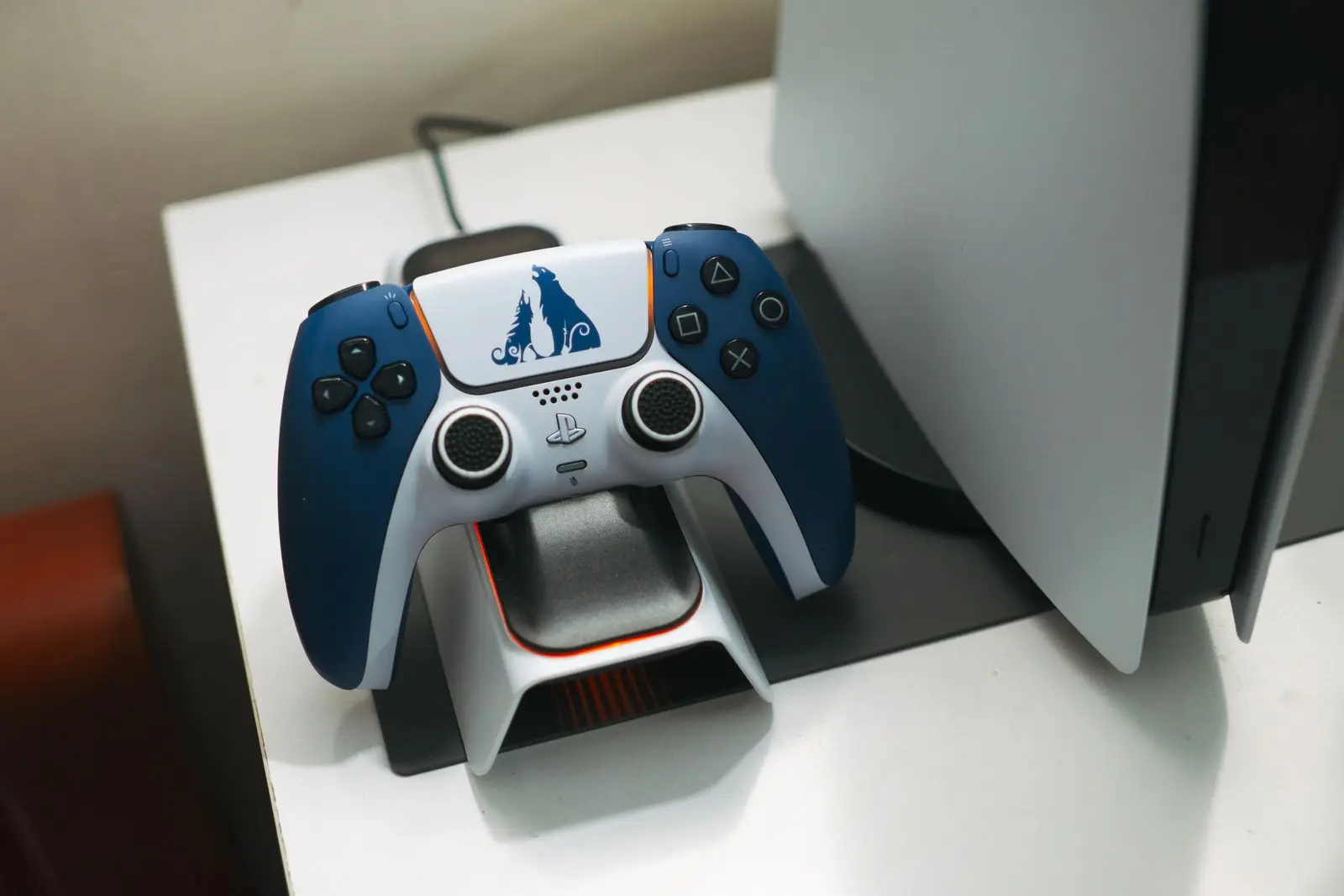 Manette PlayStation 5 DualSense posée sur sa station de charge à côté de la console.