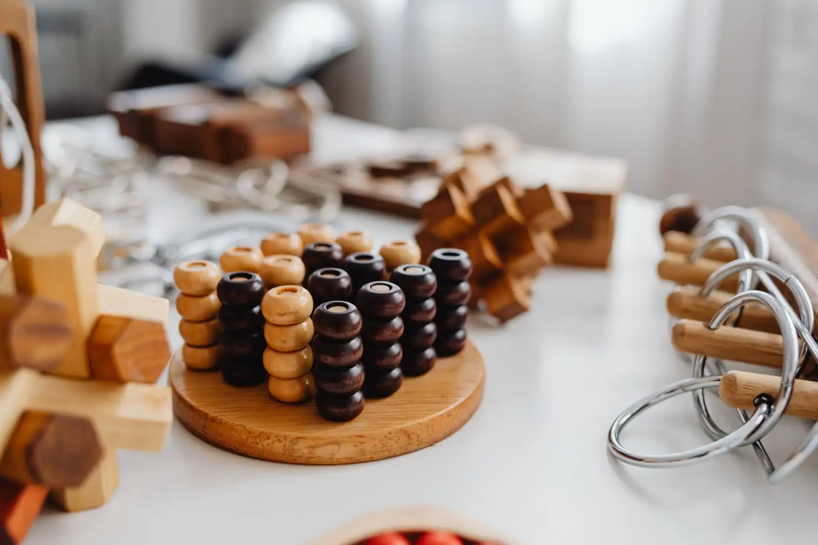 Casse-têtes de logique en bois et anneaux métalliques posés sur une table claire.