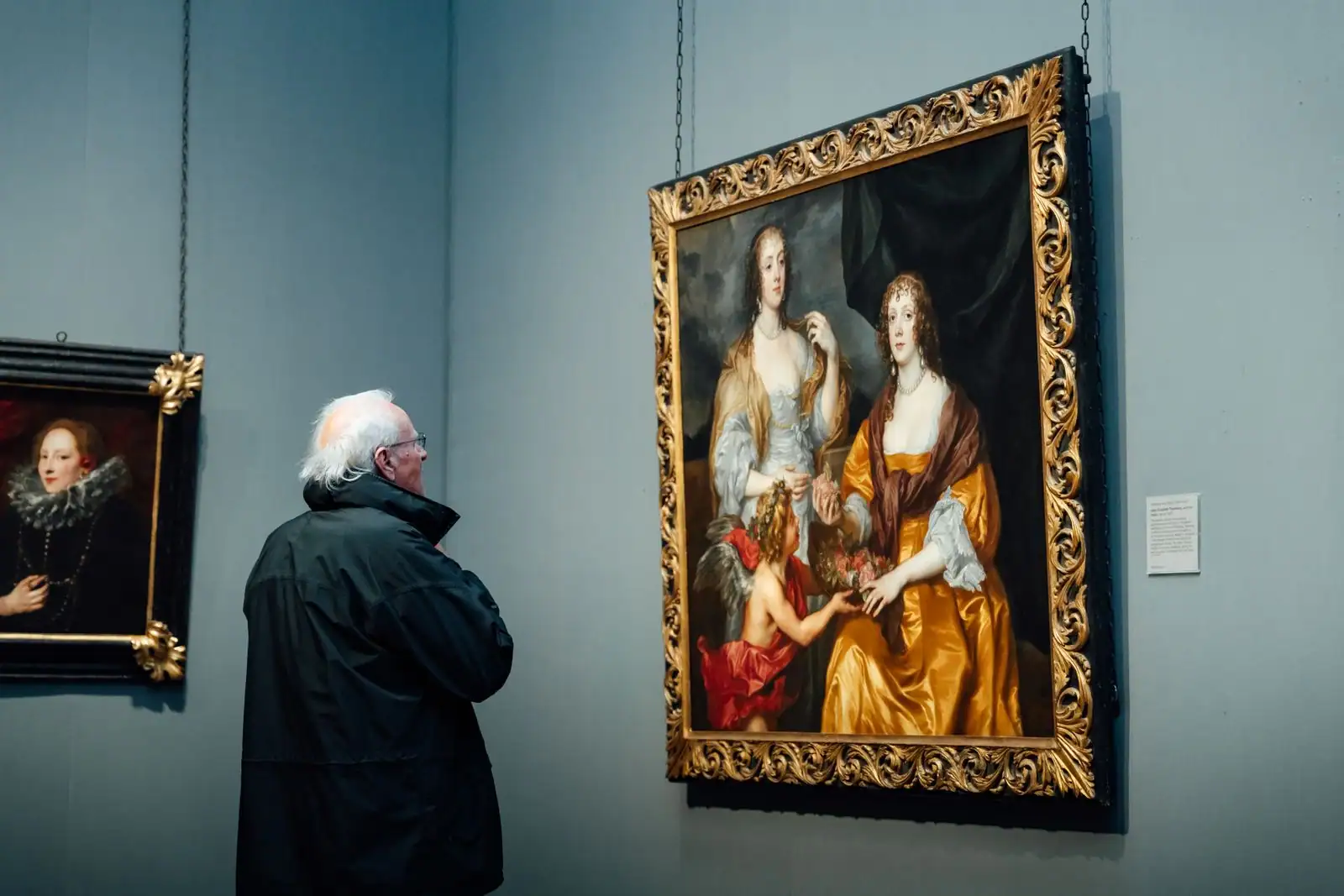 Visiteur observant une grande peinture classique encadrée d'or au mur d'une salle de musée.