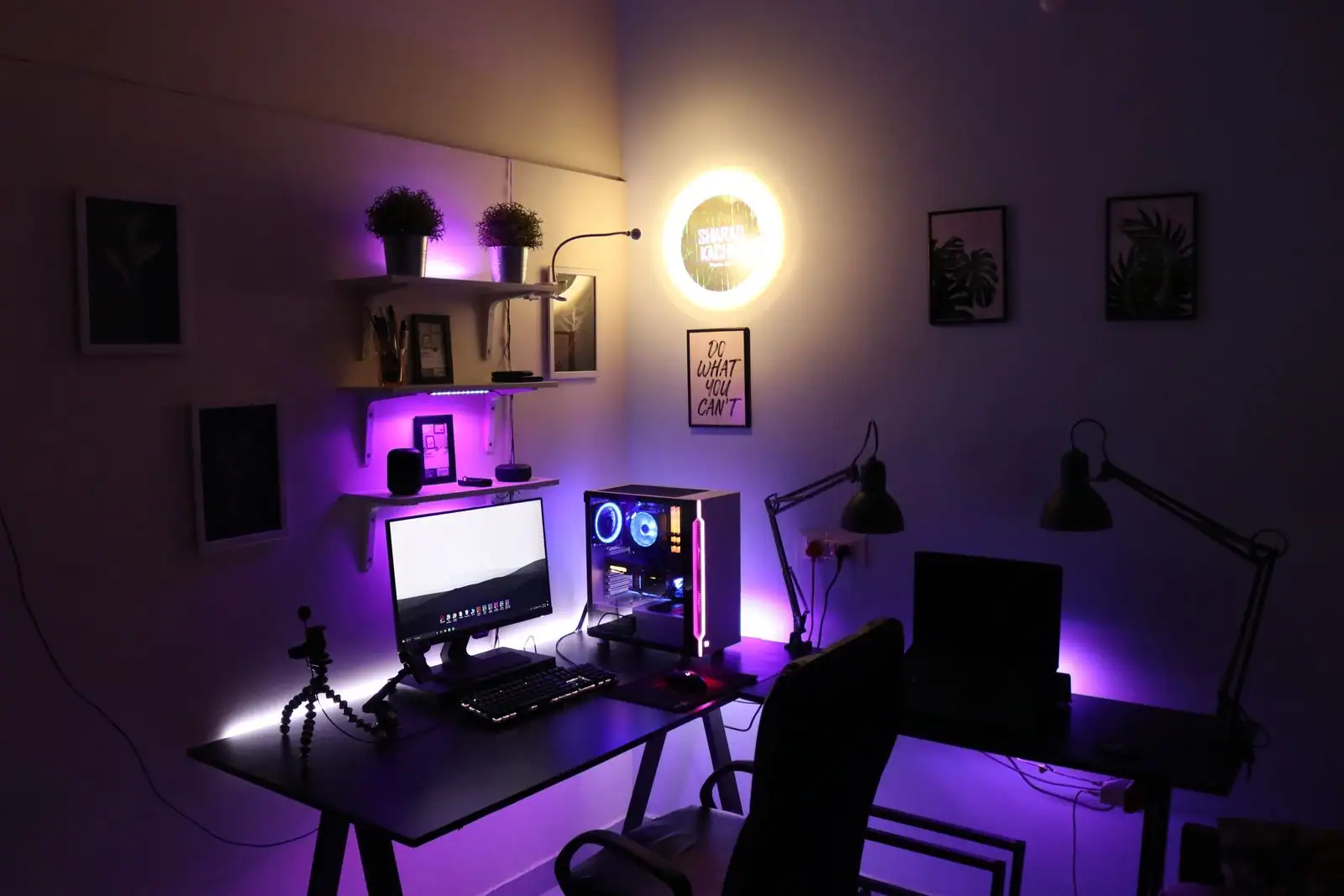 Bureau de streaming avec ordinateur RGB, écran et éclairage d'ambiance violet dans une pièce sombre.