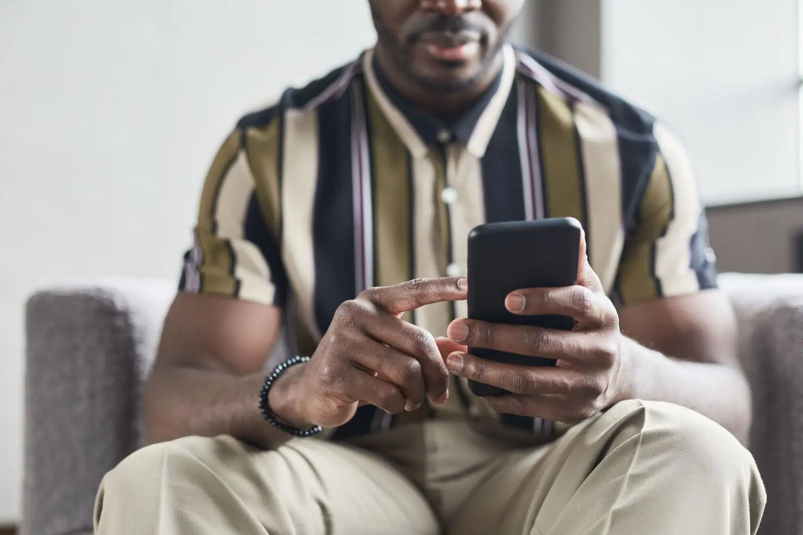 Homme assis utilisant un smartphone, illustration de l'usage d'une application bancaire mobile