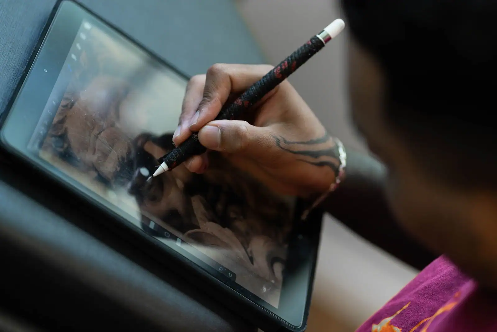 Main tenant un stylet sur l'écran d'une tablette tactile, en train de tracer un dessin numérique.