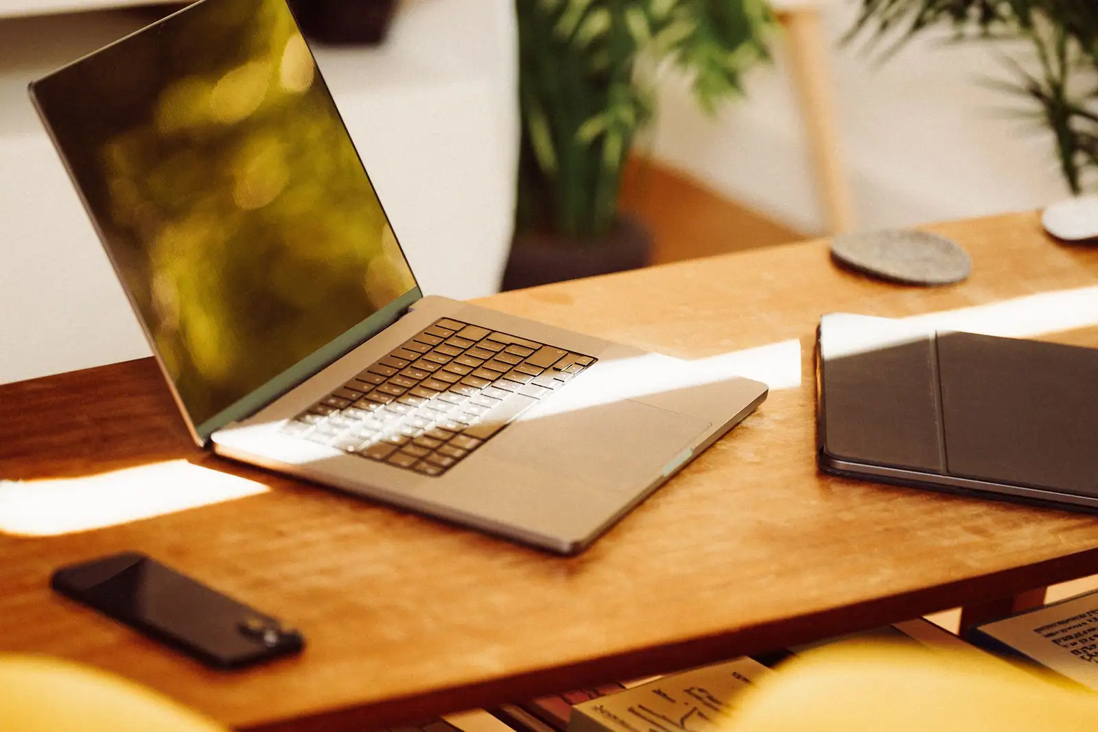 Ordinateur portable ouvert sur un bureau en bois, smartphone et tablette posés de part et d’autre