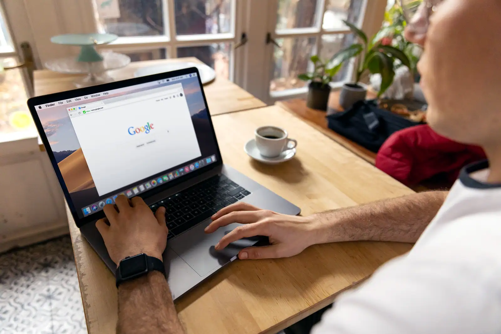 Personne attablée devant un ordinateur portable ouvert sur la page d'accueil d'un moteur de recherche