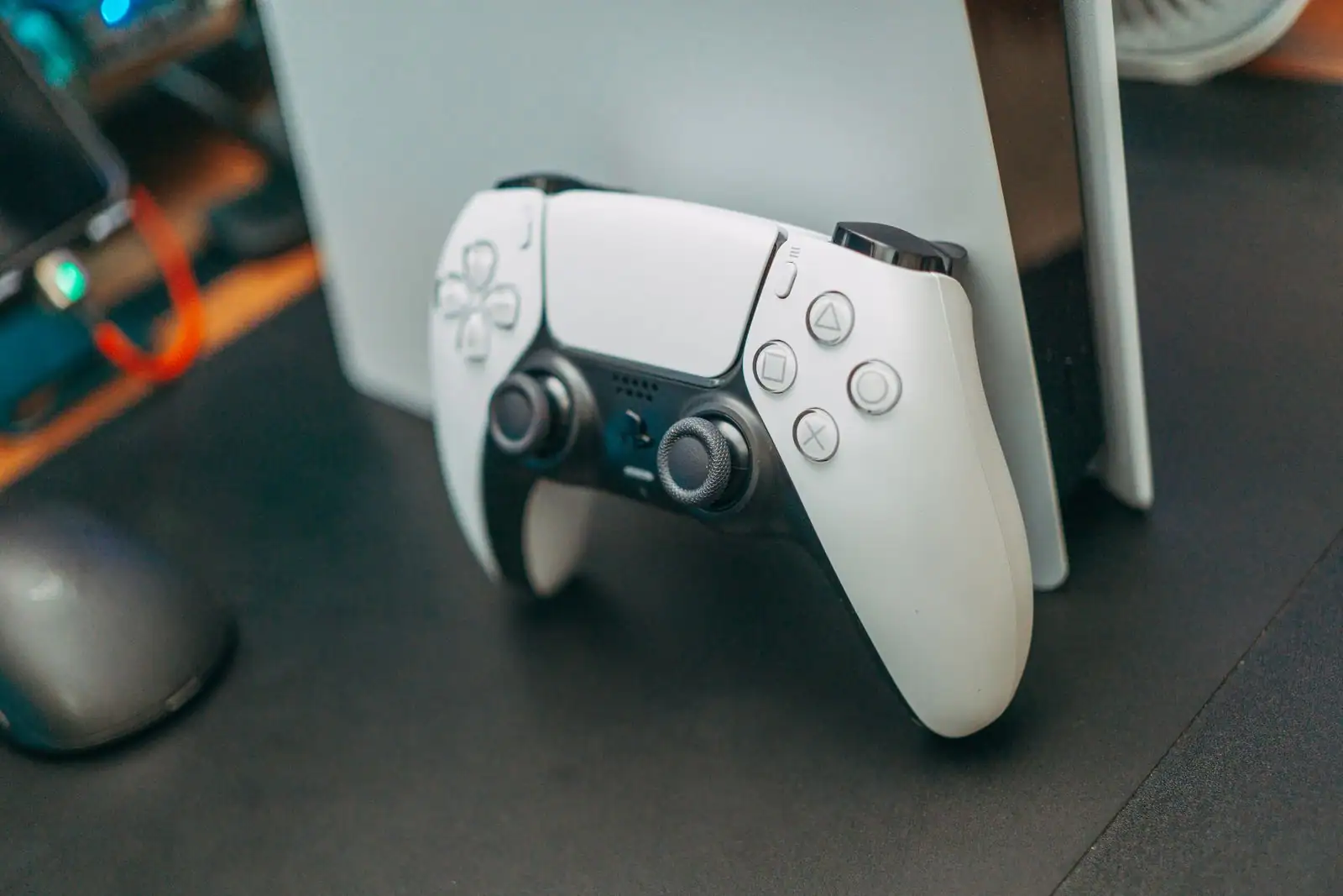 Manette DualSense blanche appuyée contre une console PlayStation 5 posée sur un bureau