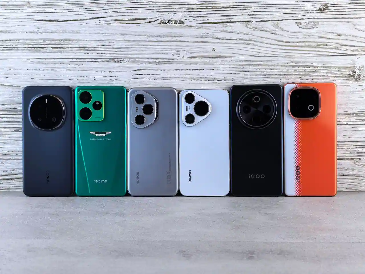 Six smartphones alignés côte à côte, vus de dos, avec des modules photo et des coloris différents
