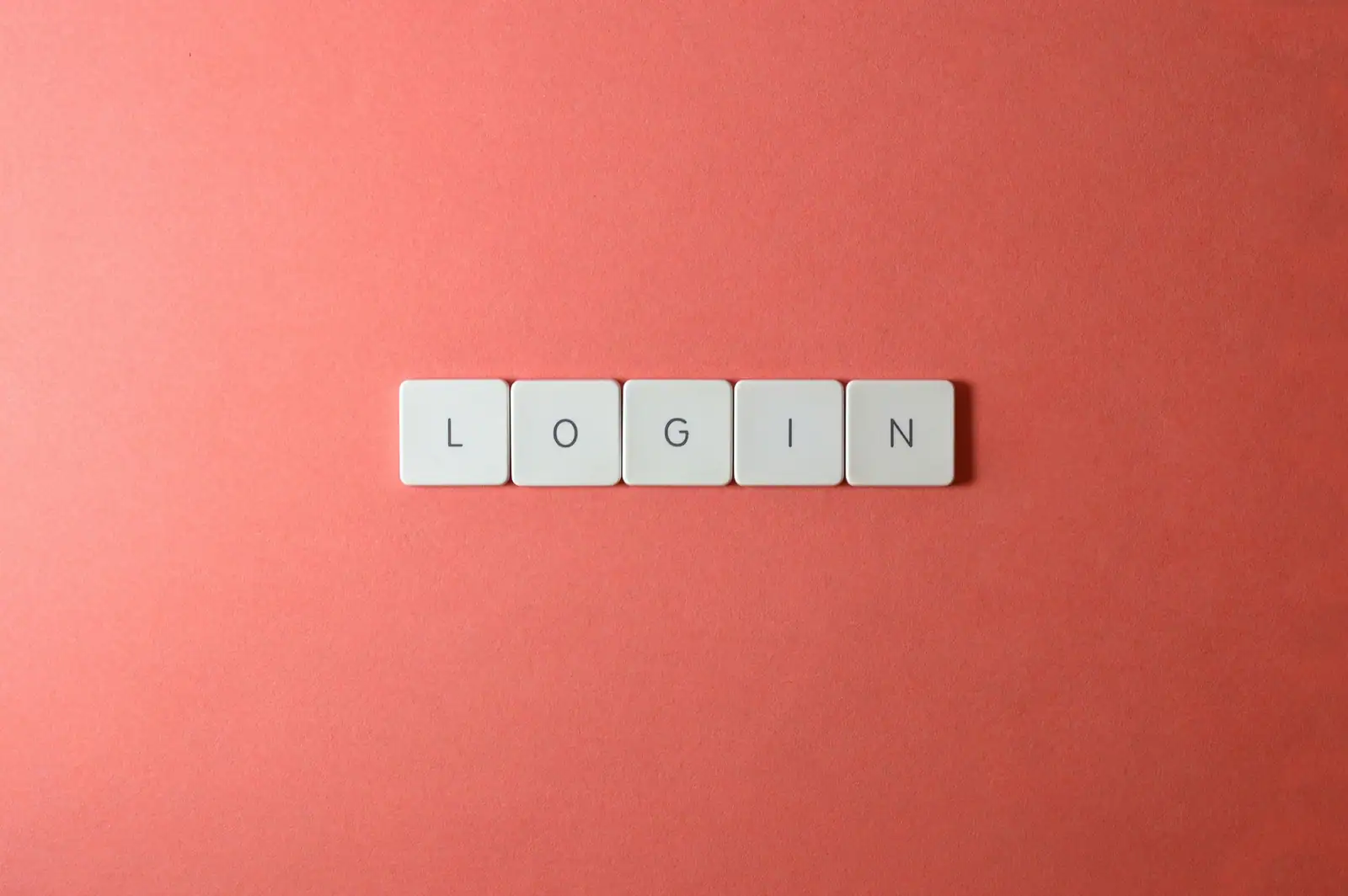 Cinq touches de clavier blanches alignées sur un fond corail forment le mot anglais login.