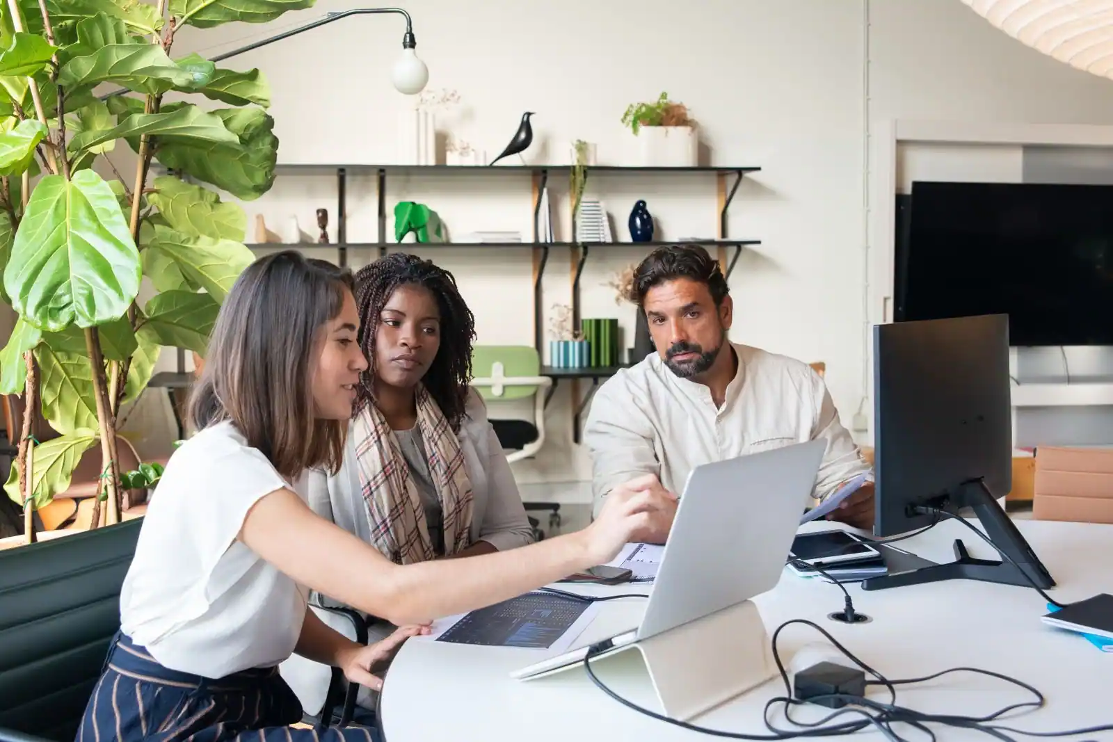 Trois collègues réunis autour d’une table de bureau, devant un ordinateur portable ouvert