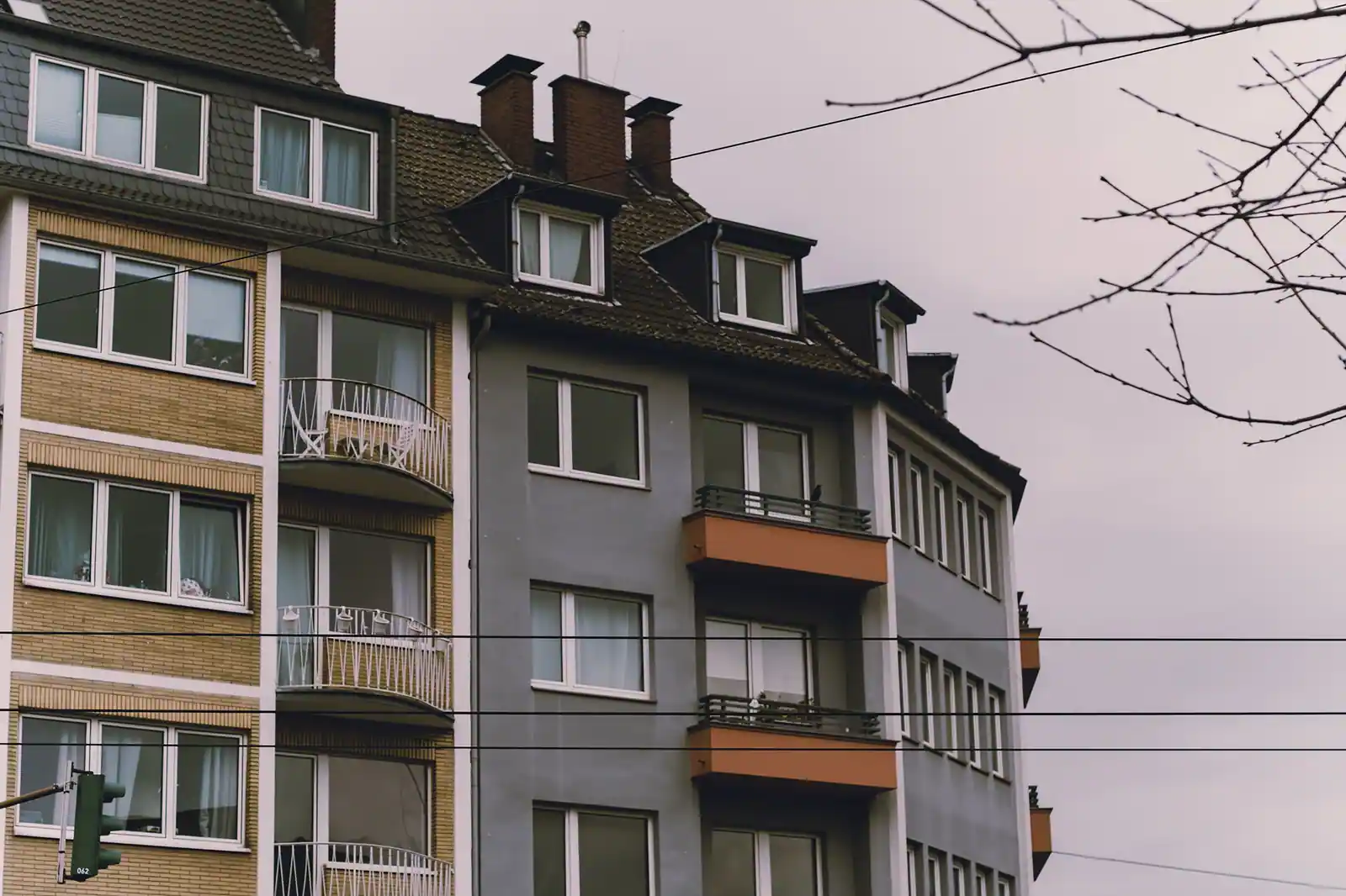 Façades d'immeubles d'habitation avec balcons et toiture en ardoise, sous un ciel couvert.