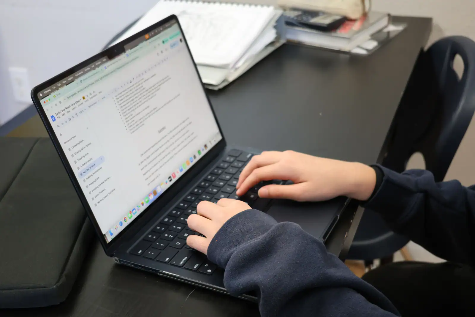 Mains sur le clavier d’un ordinateur portable, écran affichant un document texte ouvert dans un navigateur