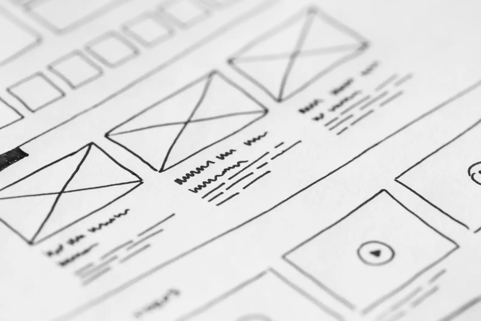 Croquis à la main d'une maquette de site web sur papier : blocs d'images, titres et lignes de texte esquissés.
