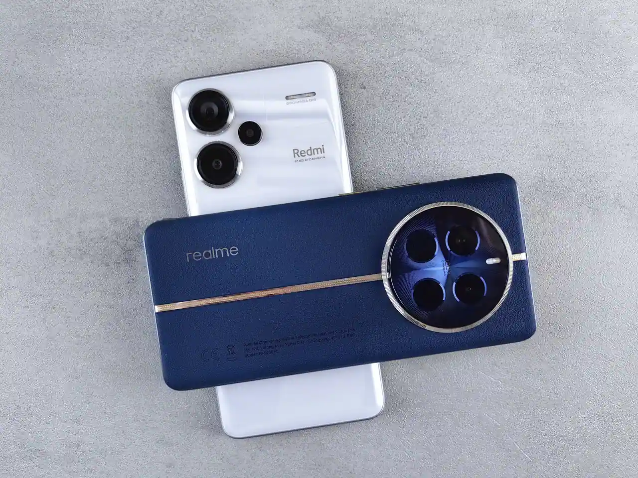 Deux smartphones de marques différentes posés l'un sur l'autre sur un plan de béton, blocs photo apparents.