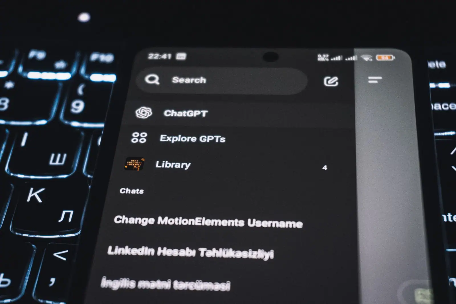 Écran d'un smartphone affichant l'interface de l'application ChatGPT, posé sur un clavier d'ordinateur