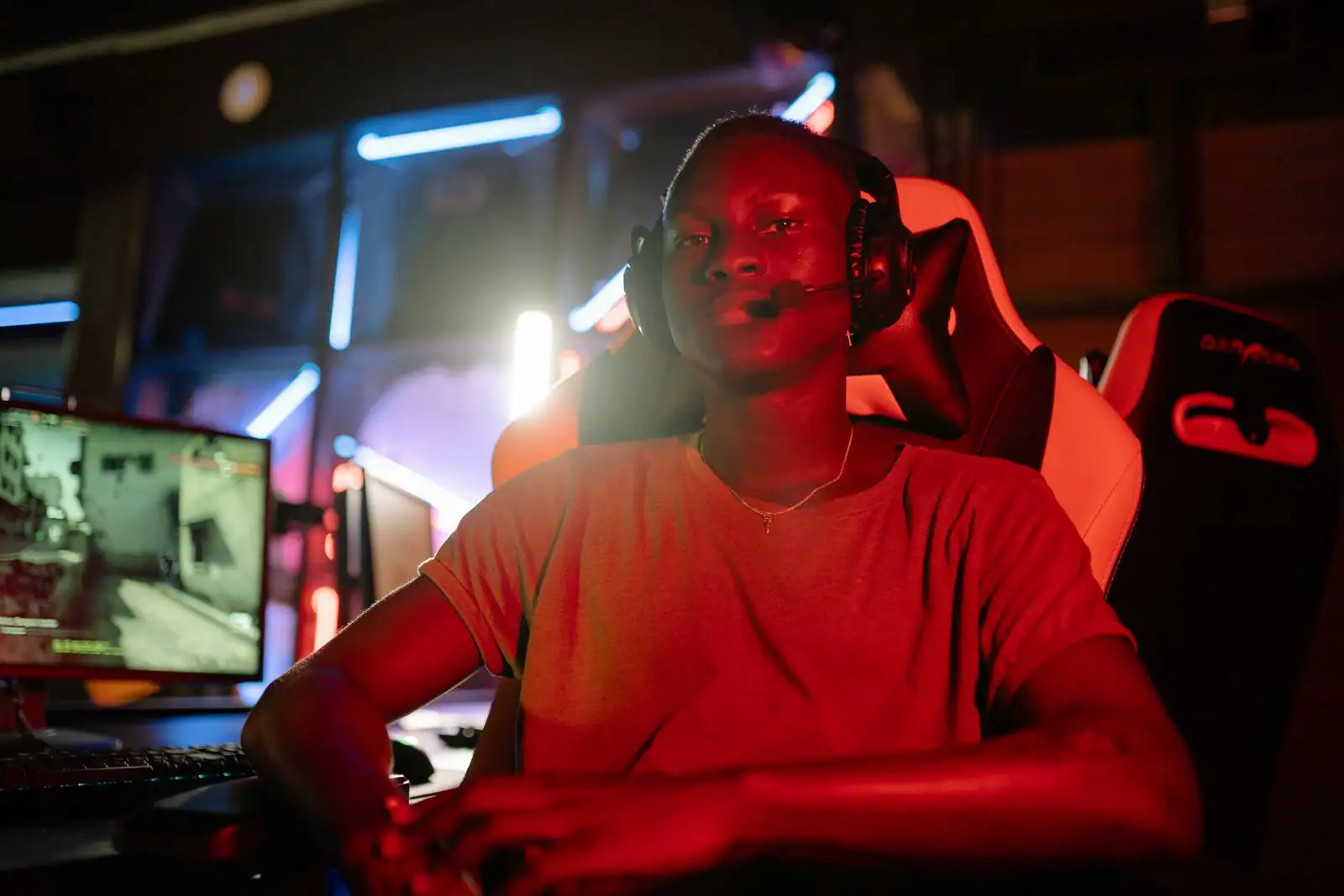 Personne portant un casque devant un écran d'ordinateur, dans une ambiance de streaming en direct.