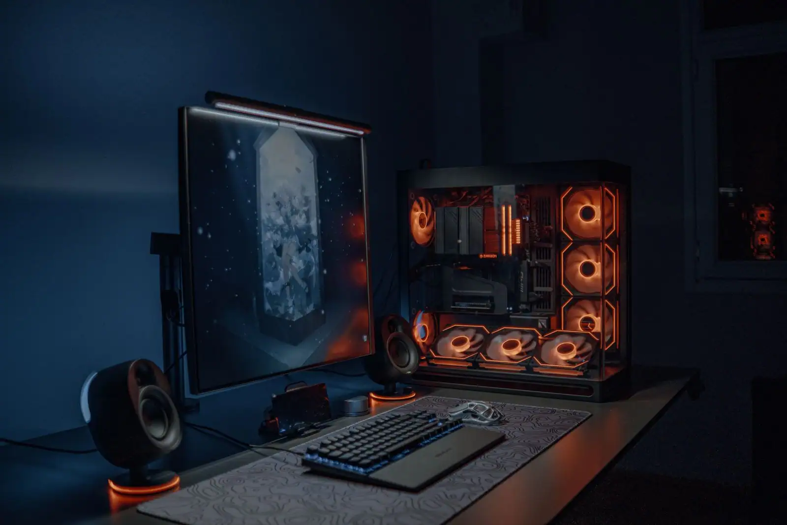 Installation de jeu vidéo avec ordinateur rétroéclairé en orange dans une pièce sombre